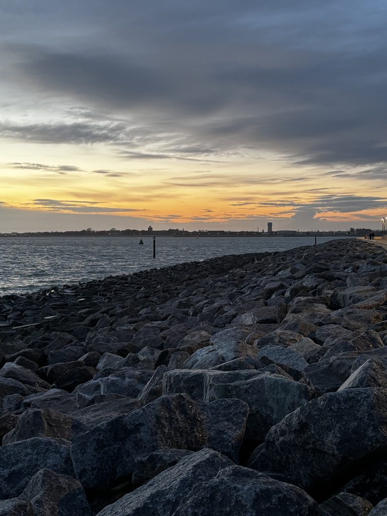 Coucher de soleil sur la mer, avec une côte rocheuse au premier plan, à Portsmouth. 