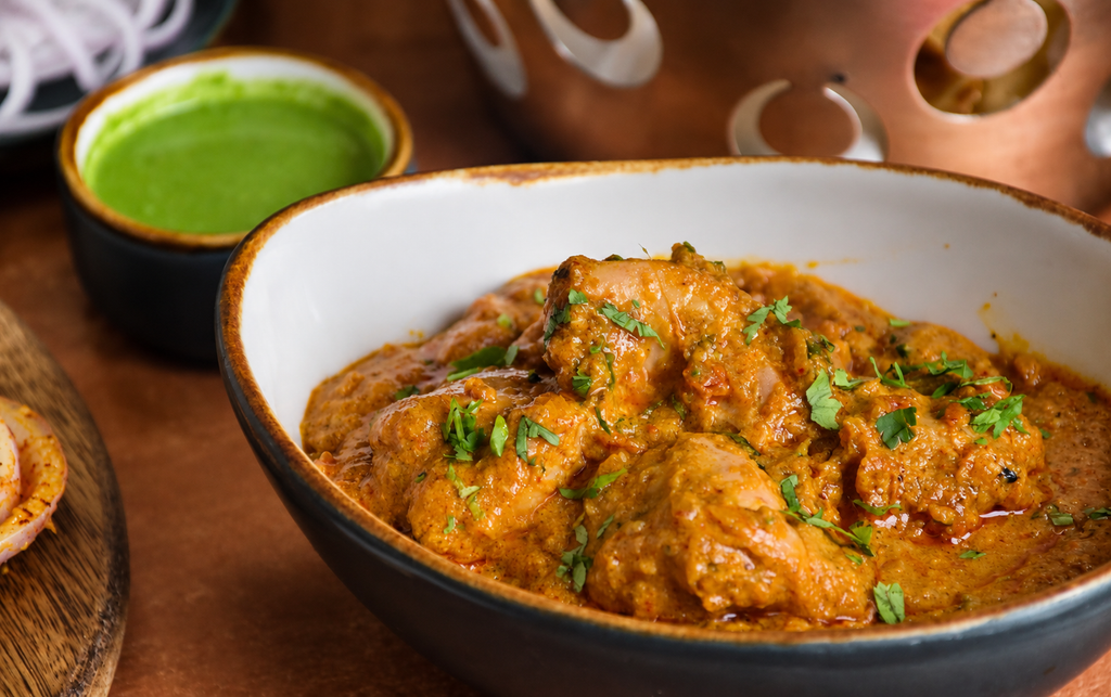 Murgir Jhol, curry de poulet bangladais dans une sauce orangée, garni de coriandre fraîche