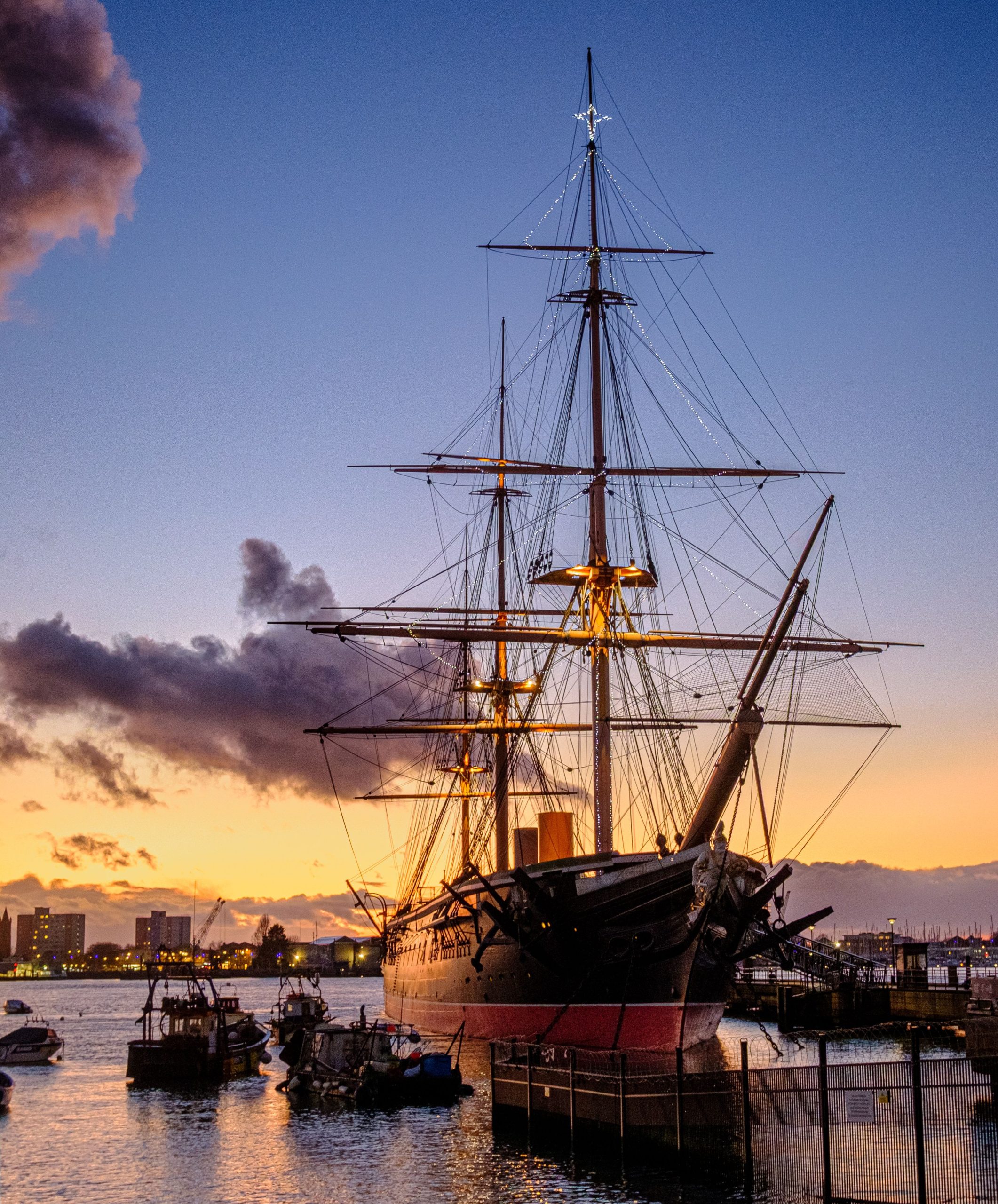 Navire historique amarré dans le port de Portsmouth au coucher du soleil. 